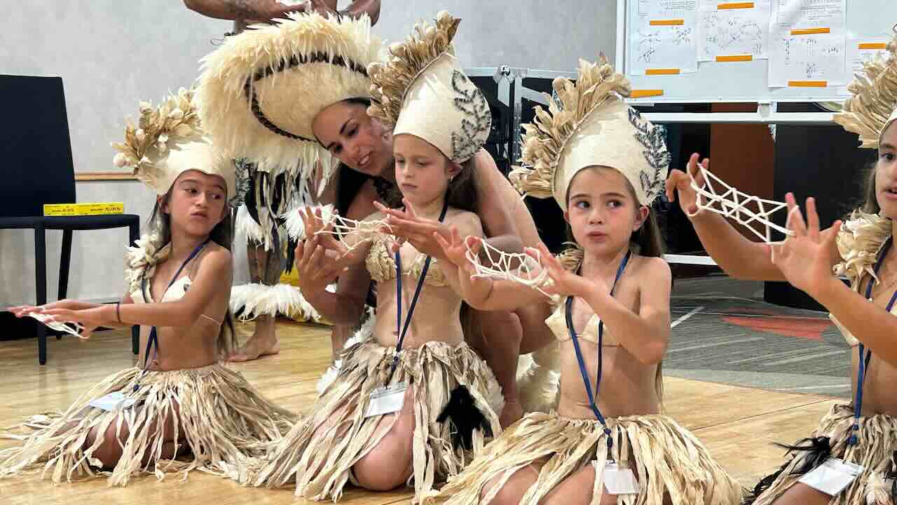 ピースボートの船内で踊りを披露するイースター島のダンサー親子たち。小さな子どもたちが伝統衣装で真剣に踊る姿から、文化の継承と家族の絆が伝わる。