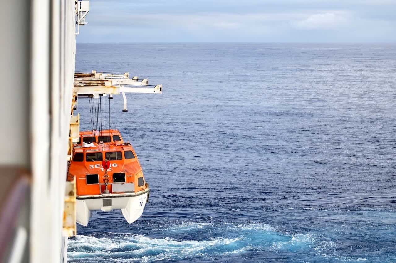 ピースボートから、イースター島への上陸に向けてテンダーボートが海面へ下ろされている様子。青い太平洋とオレンジの救命艇のコントラストが印象的。