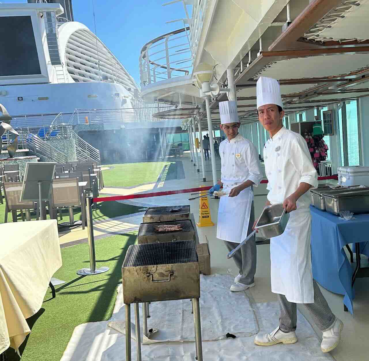 ピースボートのデッキで開催されたバーベキューイベント。シェフたちが青空の下で肉を焼き、乗客がゆったりとした時間を楽しむ寄港日のひととき。