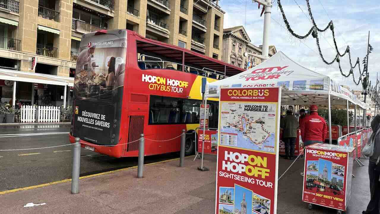 マルセイユ旧港に停車する観光バス「HOP-ON HOP-OFF（Colorbüs）」の受付テントと赤い二階建てバス