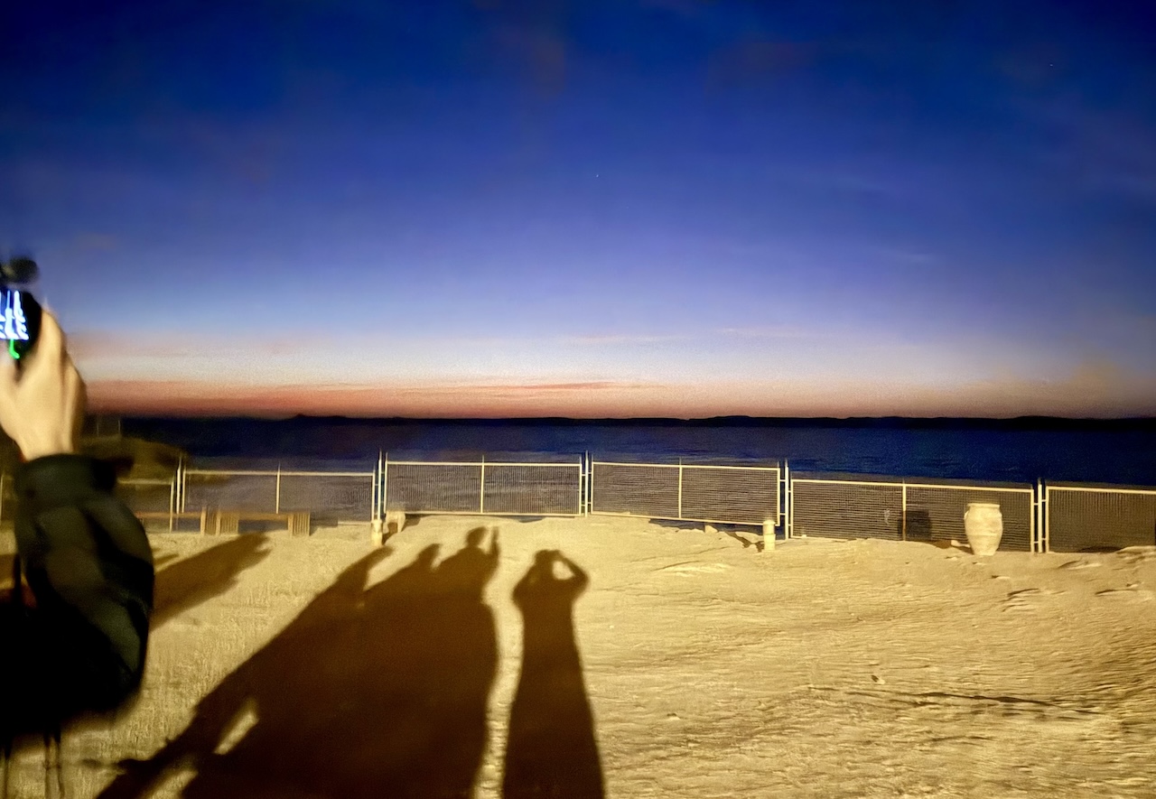 夜明け前の湖と影になった観光客たち