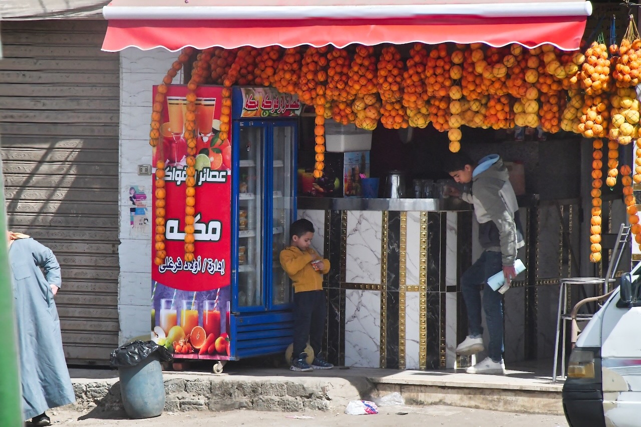 オレンジが飾られたジューススタンドと子ども
