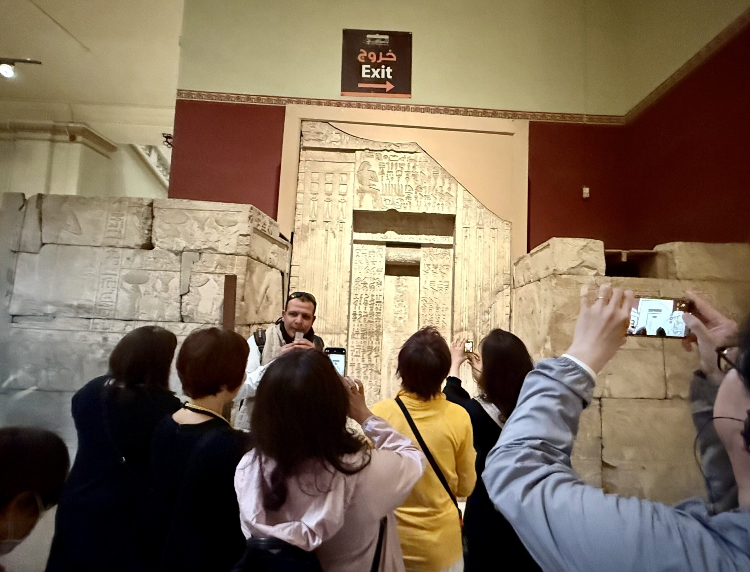 EXITサインの前で説明を受けるツアー参加者たち