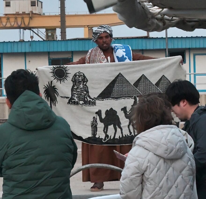 エジプトでスカーフを広げて見せる商人とツアー客