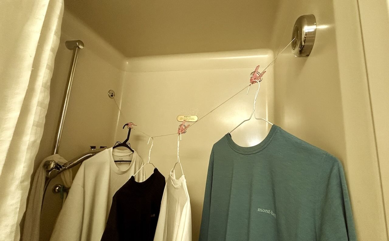 ピースボート船室のシャワールームで洗濯物を水切りしている様子