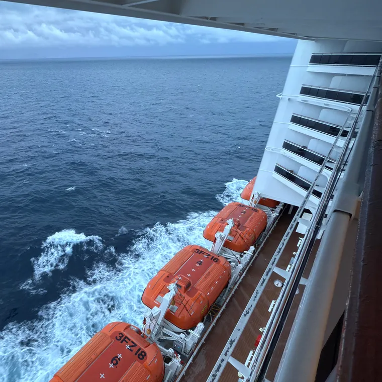 MSCスプレンディダの船体横に並ぶオレンジ色の救命艇と航跡