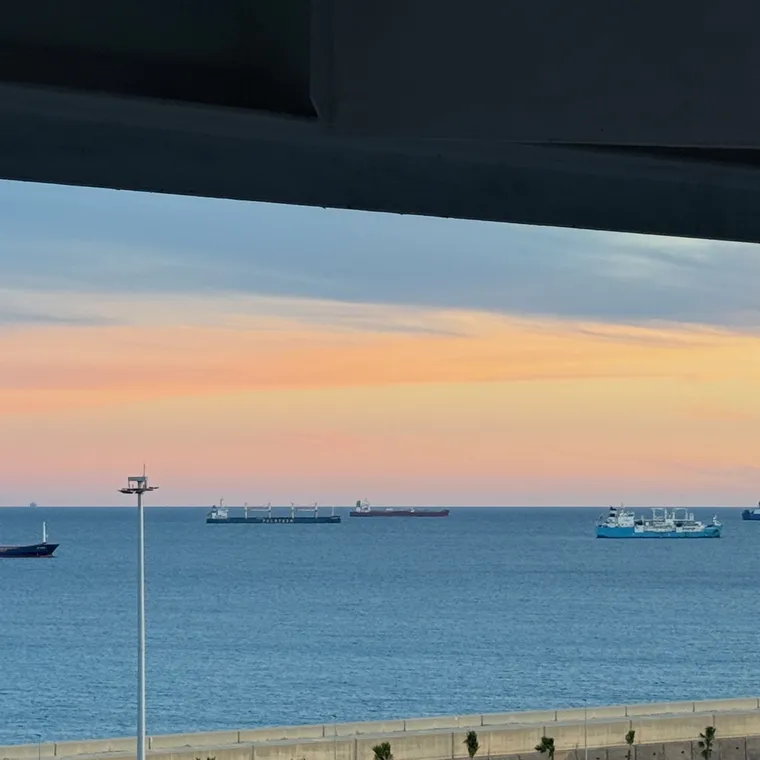 バルコニーから見た淡いピンク色の夕空と港に浮かぶ船