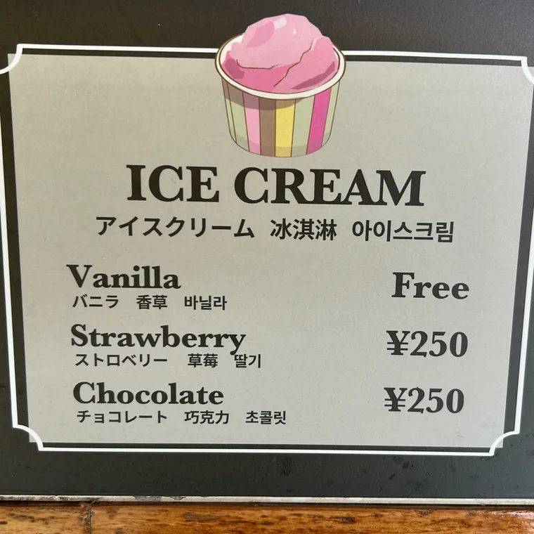 バニラは無料でストロベリーとチョコレートは有料と書かれたアイスクリームの案内