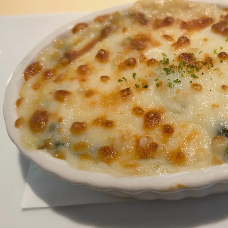 表面のチーズに焼き色がついた白い器のグラタン