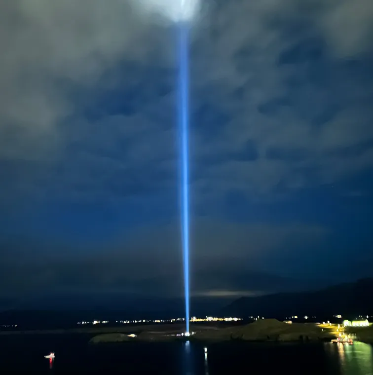 レイキャビクの海辺から夜空へ伸びるイマジン・ピース・タワーの青い光