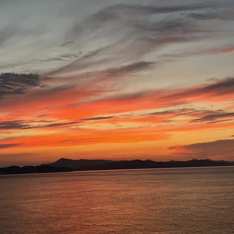 日本沿岸の島影と赤く染まる出航後最初の夕日