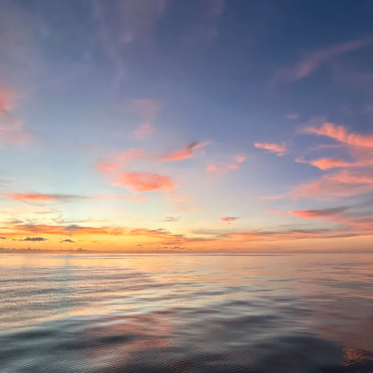 島影の上に赤とオレンジ色が広がる穏やかなカリブ海の夕空