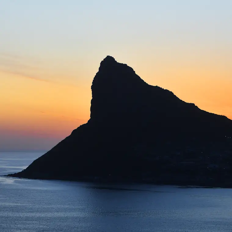 夕焼けの空と海を背景に黒く浮かぶ山の稜線