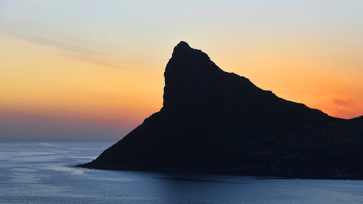 夕焼けの空と海を背景に黒く浮かぶ山の稜線