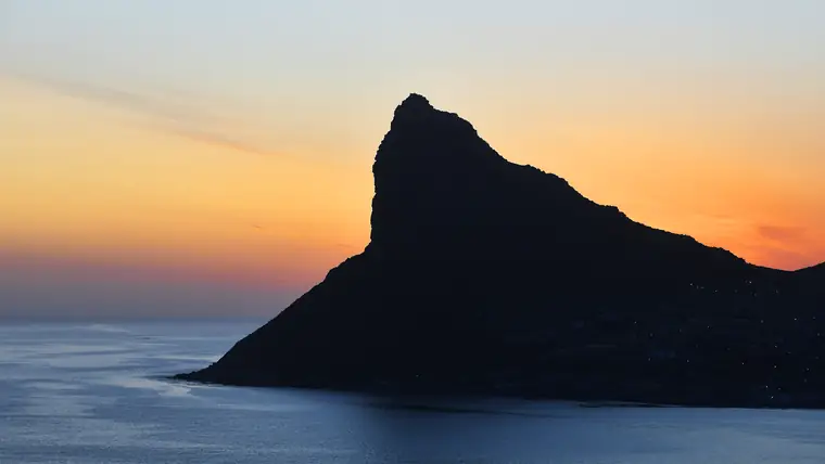 夕焼けの空と海を背景に黒く浮かぶ山の稜線