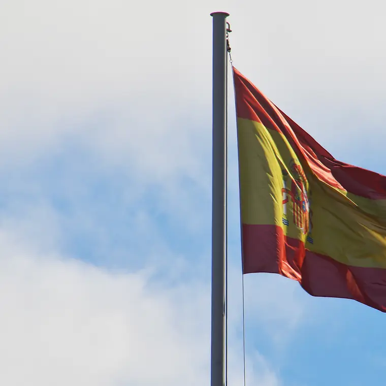 雲のある青空にはためくスペイン国旗