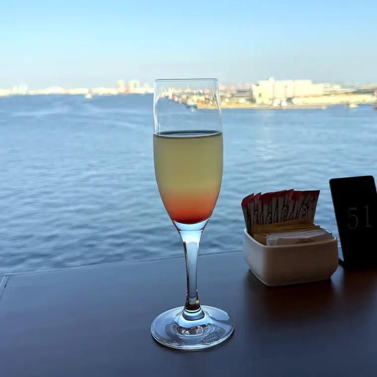 パームコートの窓際のテーブルに置かれたグラスと海の景色