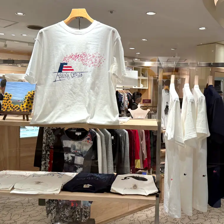 飛鳥Ⅱの船内ショップに並ぶ白いオリジナルTシャツと衣類