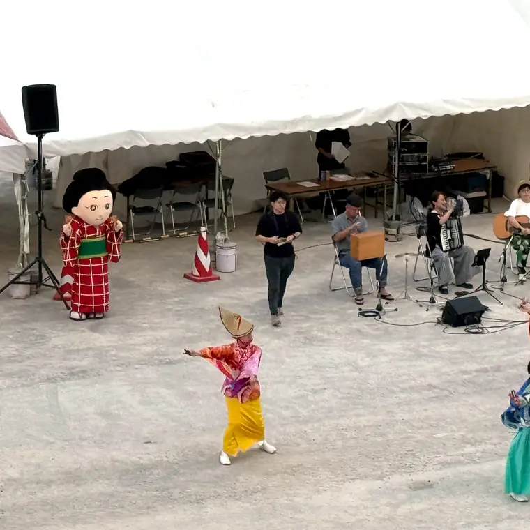 高知港の岸壁でよさこい踊りを披露する人々と飛鳥Ⅱの出港風景