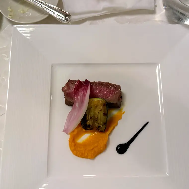 白い四角い皿に肉料理と付け合わせが盛られた洋食のメイン
