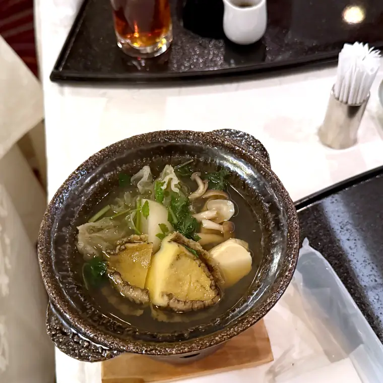 黒い器にあわびや野菜が盛られた和食料理