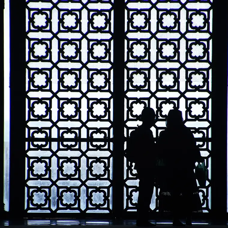 幾何学模様の窓を背に黒い影になった人たち