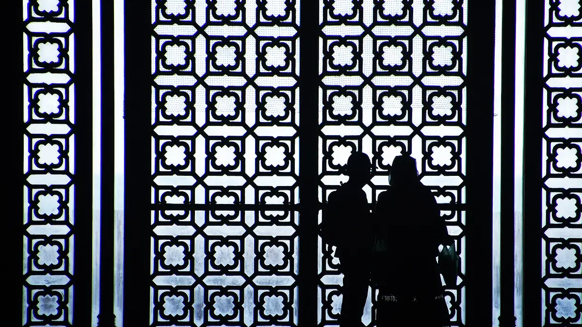 幾何学模様の窓を背に黒い影になった人たち