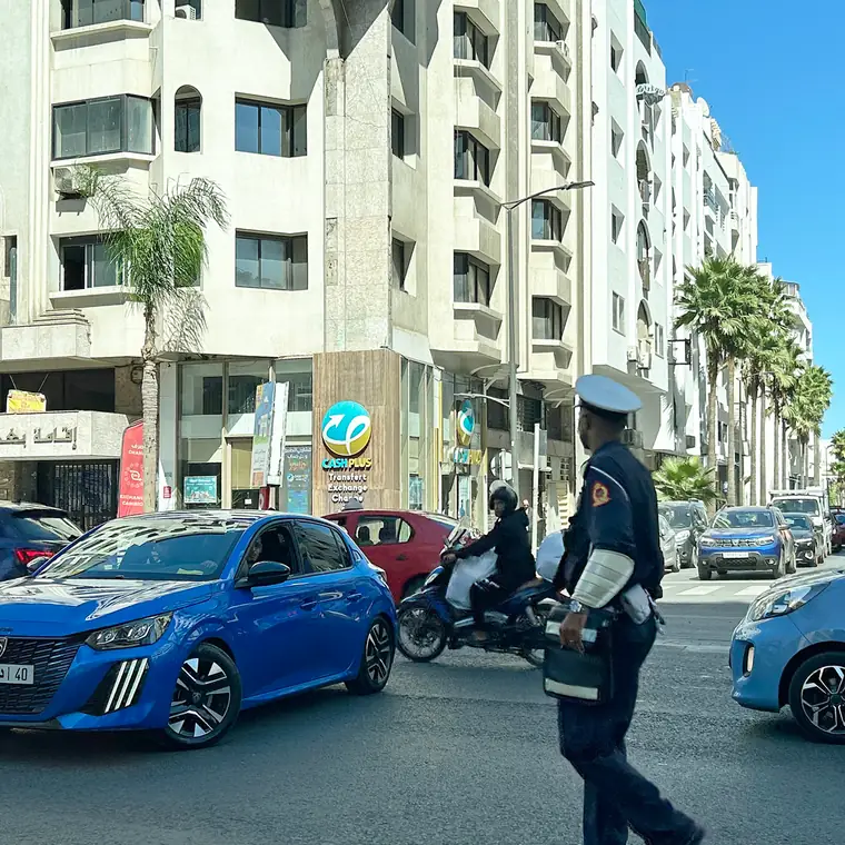 白い建物の前を車やバイクが行き交うカサブランカの通り