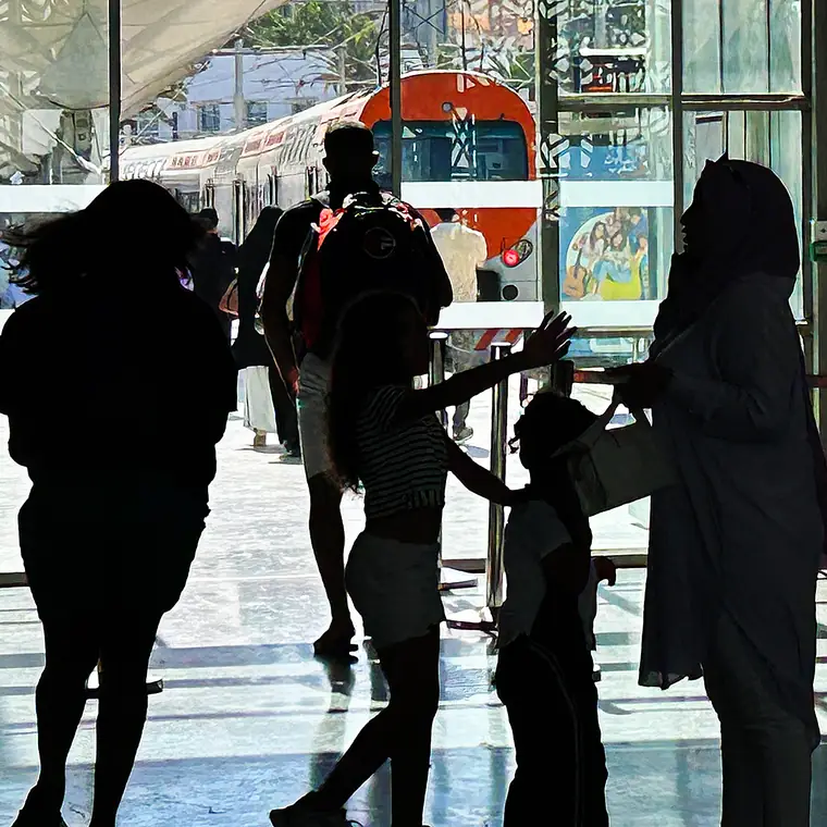 大きなガラス窓を背に影になった駅構内の人たち