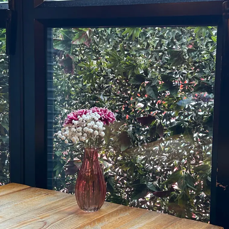 窓辺の花瓶と、窓の外に見える緑