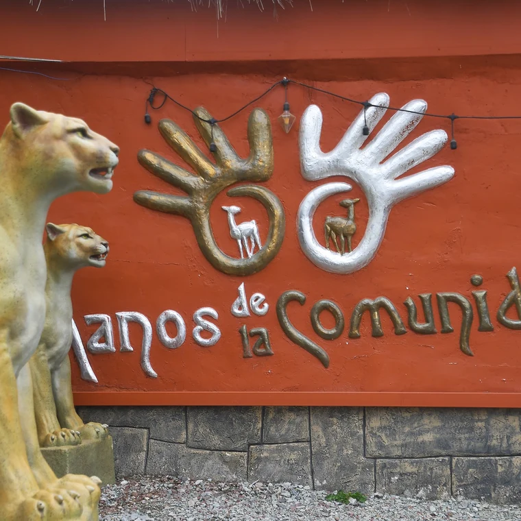 クスコ近郊マノス・デ・ラ・コムニダの看板と動物の像